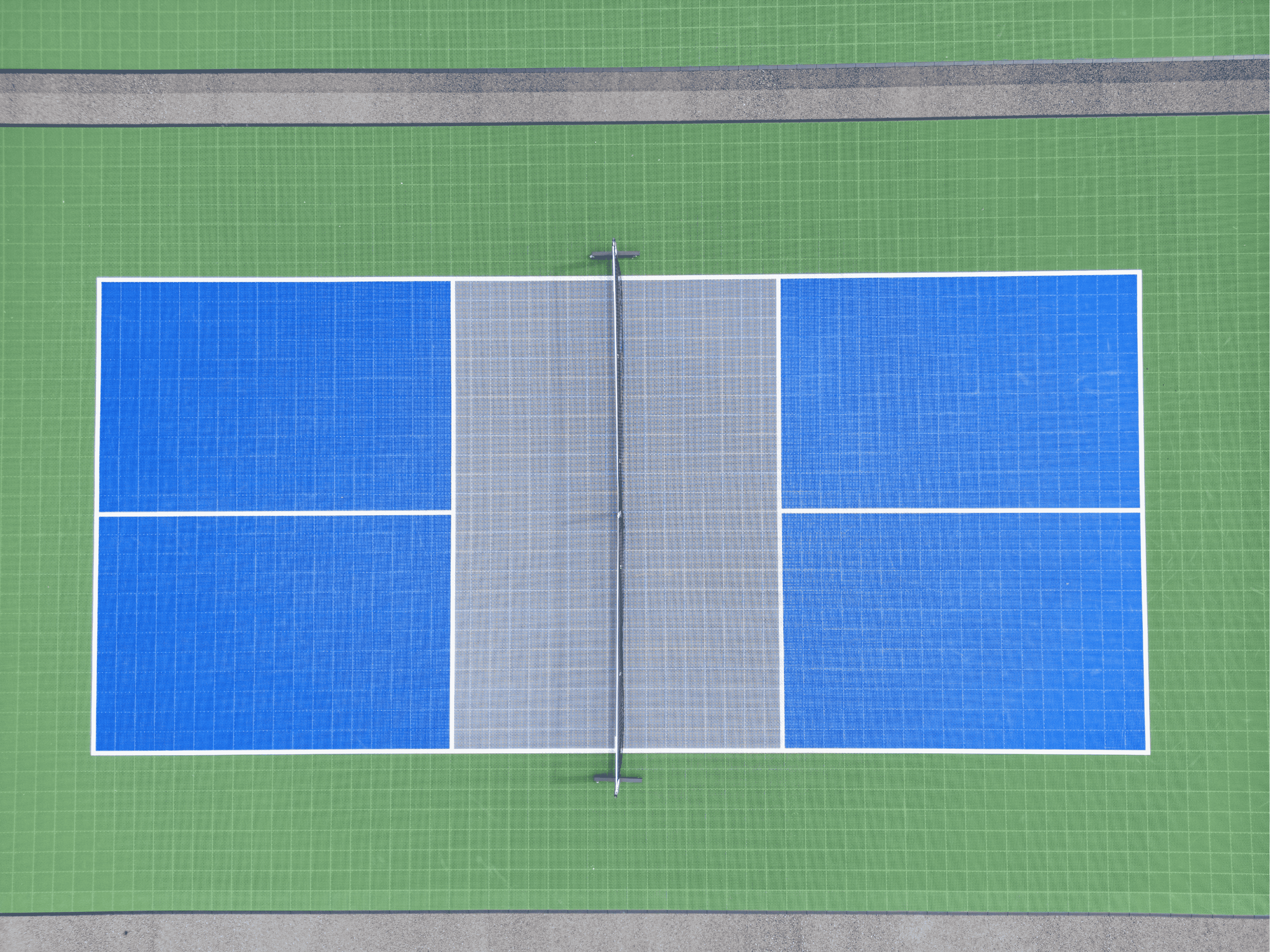 Draufsicht auf ein einzelnes Pickleball-Spielfeld mit blauer Spielfläche, grauer Mittelzone und grüner Umrandung.